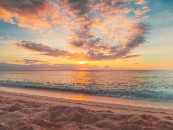 Sunset over the Pacific Ocean on a Hawaiian beach, symbolizing peace and renewal in the Kingdom of Hawaiʻi