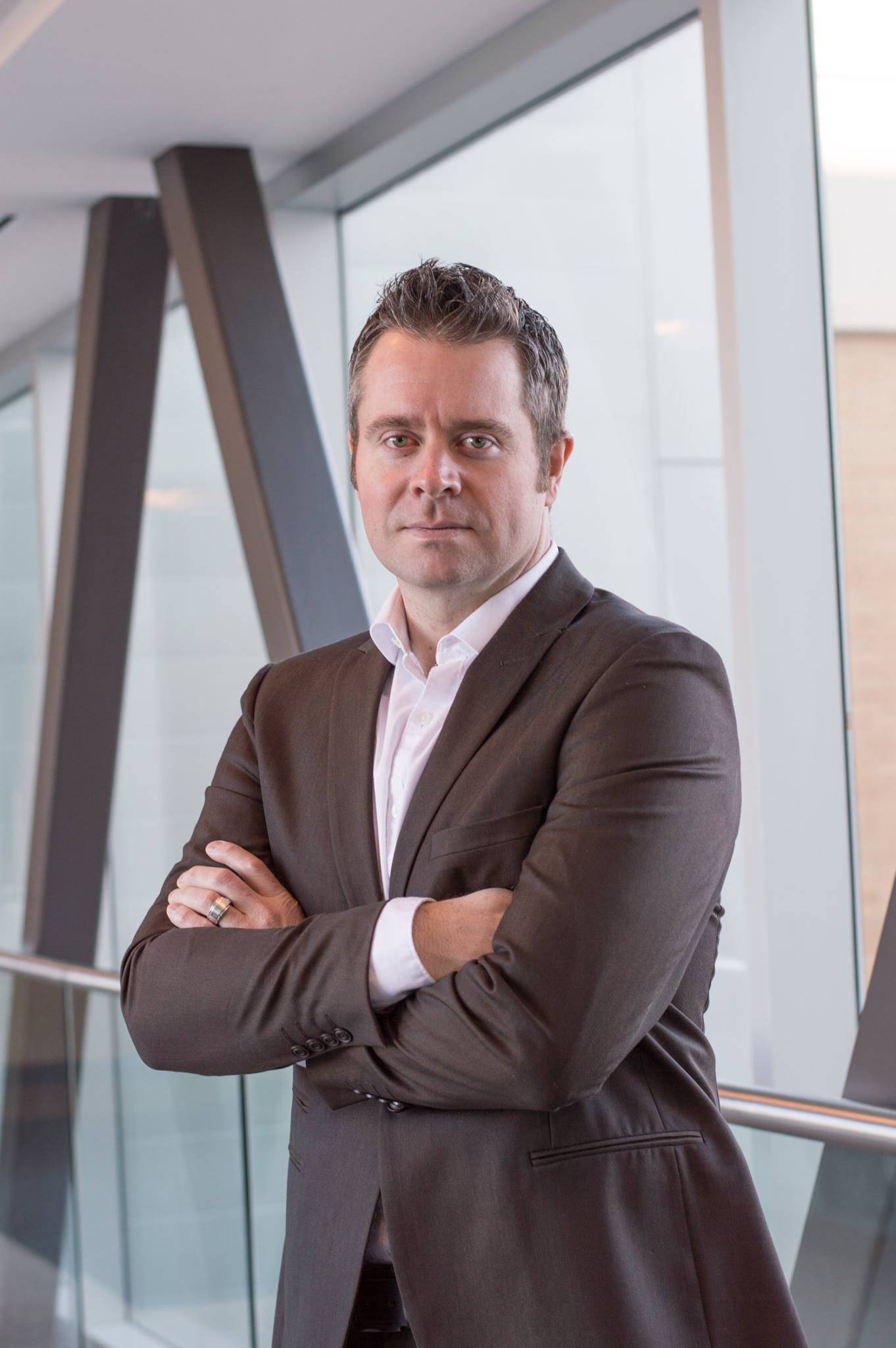 Rhett Hoffmeister, appointed as Minister of Infrastructure, Housing, and Community Development for the Kingdom of Hawaiʻi, standing confidently in a modern setting wearing a suit.