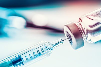 Close-up of a syringe drawing COVID-19 vaccine from a vial for immunization